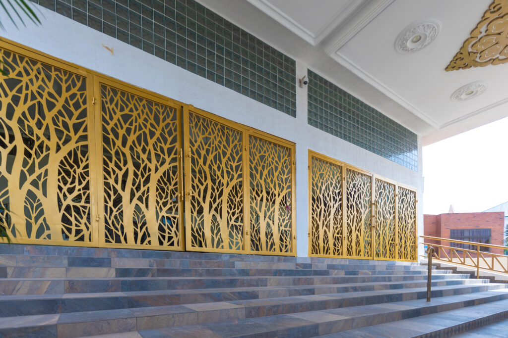 Laser cut gold screens with a tree pattern seen along the steps of a building entrance