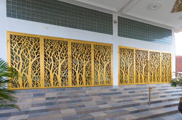 Gold laser cut screens with a tree branch pattern lining the entrance of a building