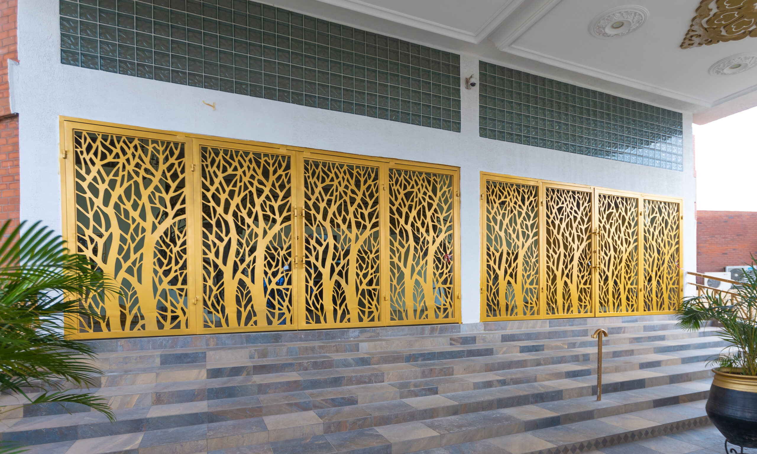 Gold finished metal screens cut with a tree pattern, fitted across a building frontage