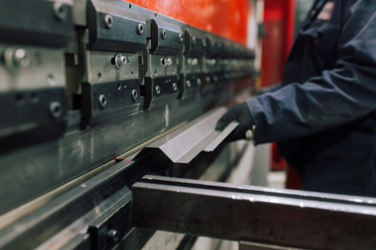 Operator feeding a steel sheet into a CNC press brake for bending